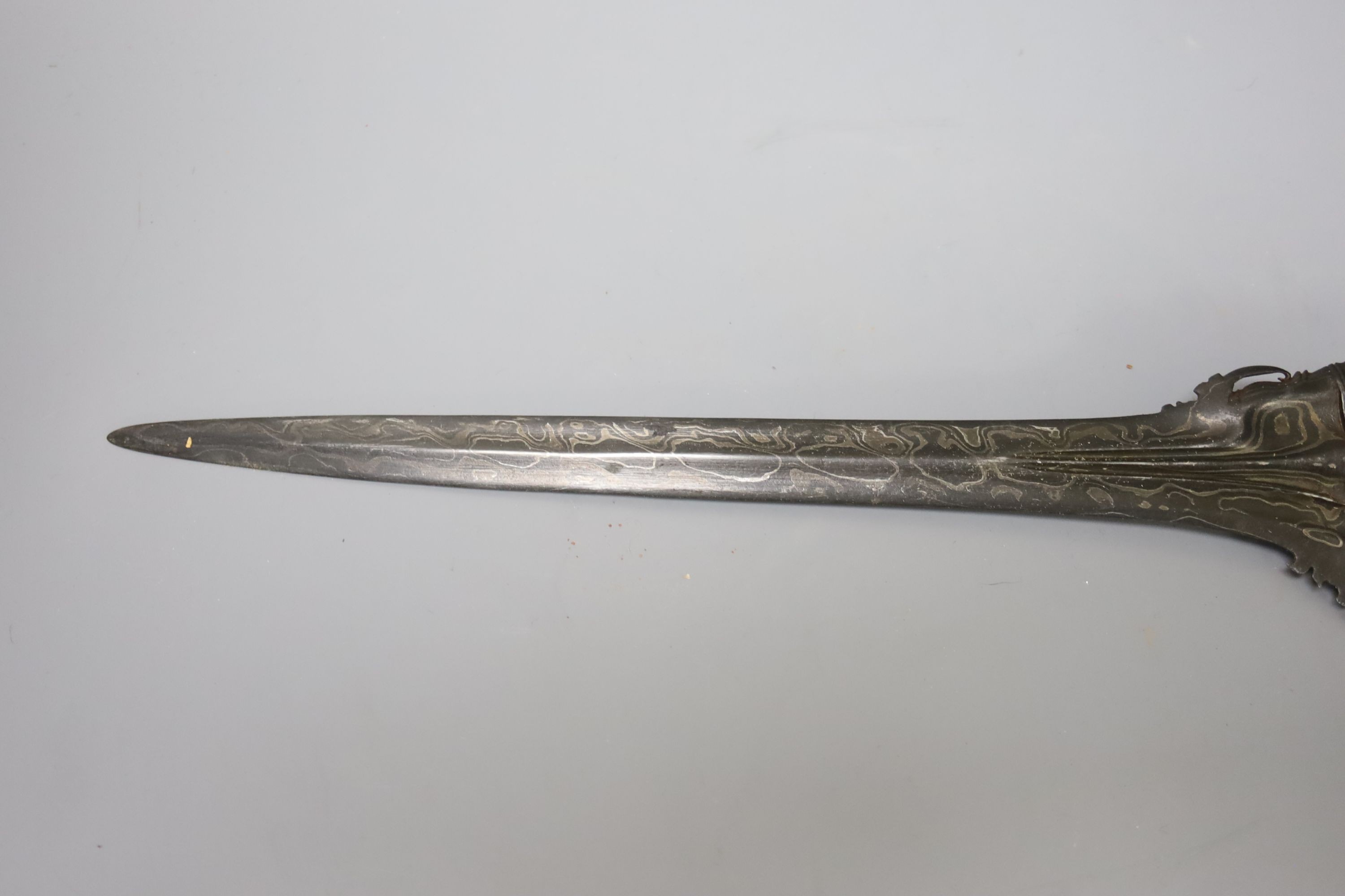 An Indonesian dagger kris, 19th century, earlier black and silver-coloured watered blade, brass hilt, wooden scabbard, blade 33cms